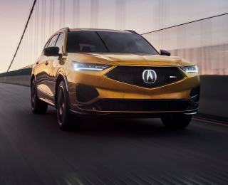 3/4 view of tiger-eye pearl-coloured MDX Type S driving on a bridge. / Vue 3/4 du MDX Type S couleur œil-de-tigre nacré sur un pont.