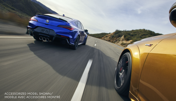 3/4 rear view of a blue Integra Type S driving on a highway alongside a gold Integra Type S.