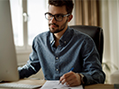 A young man works at a computer. / Un jeune homme travaille à l’ordinateur.